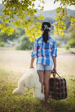 女孩带着玩具熊和手提箱