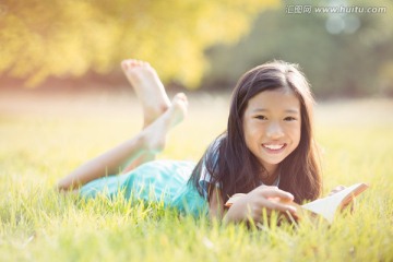 微笑的女孩躺在草地上看书