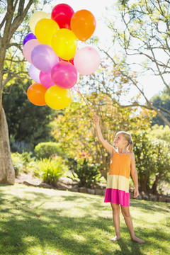 面带微笑的女孩拿着气球在公园里