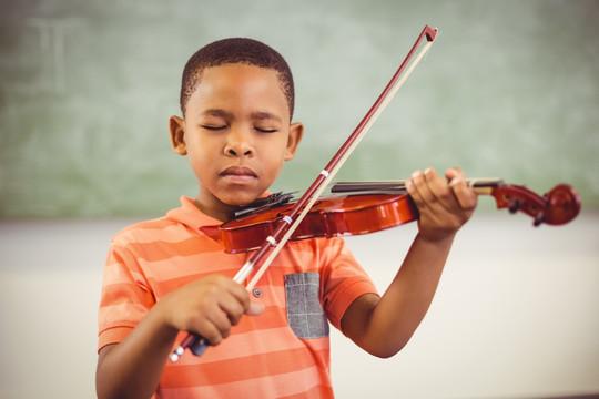 在教室里拉小提琴的小男孩