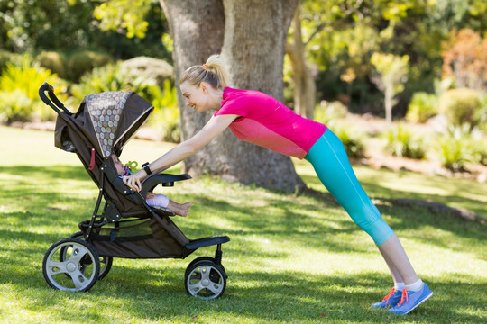女人推着婴儿车在公园做锻炼