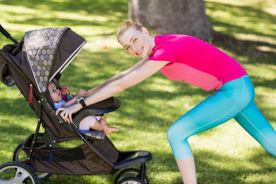 女人推着婴儿车在公园运动