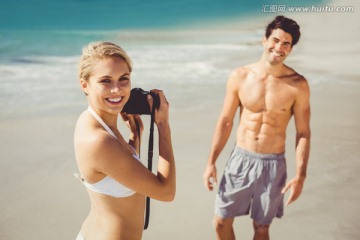 拿着相机在海边给男友拍照
