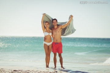 拿着毛巾在沙滩上的夫妇