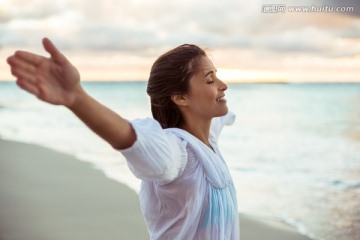 在海边举起手臂的女人