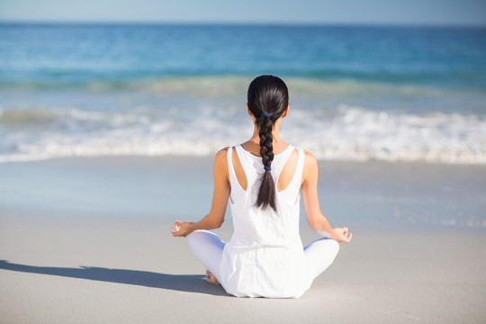 坐在沙滩上练瑜伽的女人