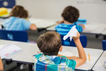 在教室里玩纸飞机的小学男生