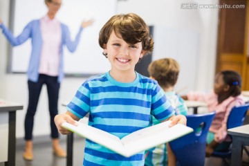 在教室里拿着课本的男学生