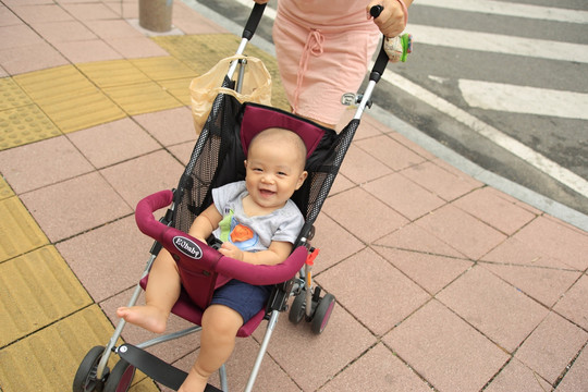 坐在婴儿车上对着镜头大笑的宝宝