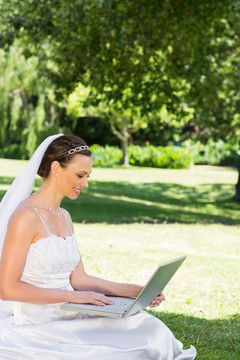 美丽的新娘在花园里用笔记本电脑