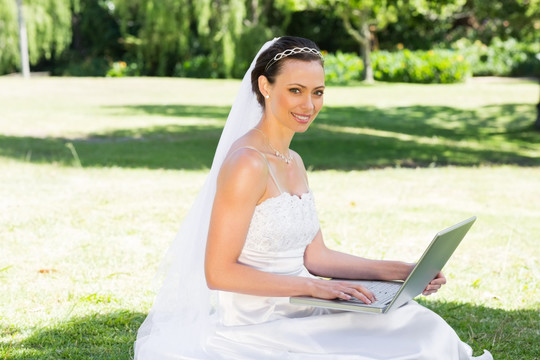 在花园里用笔记本电脑的新娘