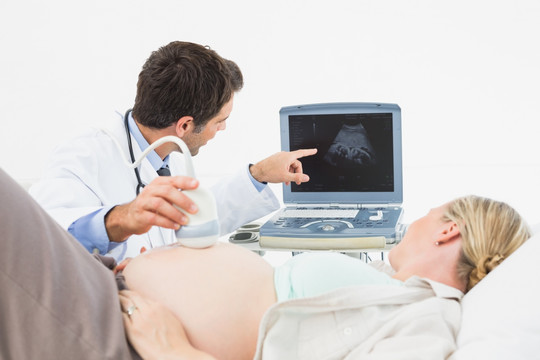 微笑的孕妇在医院接受超声检查