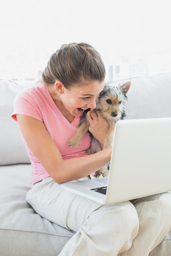 抱着狗狗在使用笔记本电脑的女人