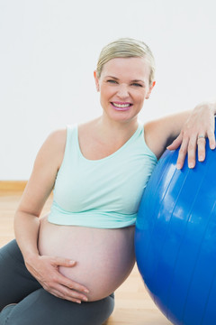 微笑着靠着健身球的孕妇