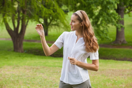 微笑的女子在公园里拿着一朵花