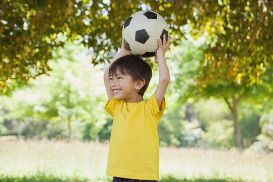 可爱的小男孩在公园里玩足球
