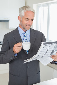在厨房里喝咖啡看报纸的男人