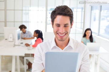 微笑着使用平板电脑的商务男人