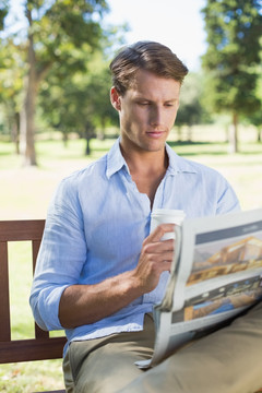 坐在公园长凳上看报纸的男人