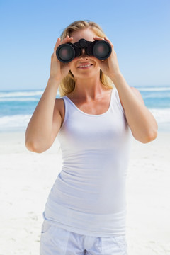 在海滩上用双筒望远镜的女人