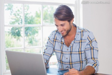 微笑着使用笔记本电脑的男人