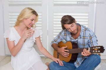 英俊的男人为他的妻子弹吉他