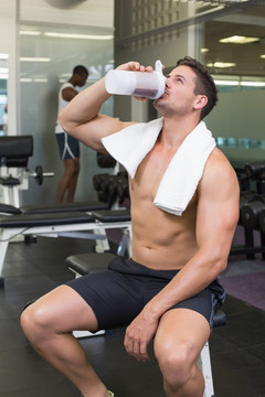 在健身房里喝水的男运动员