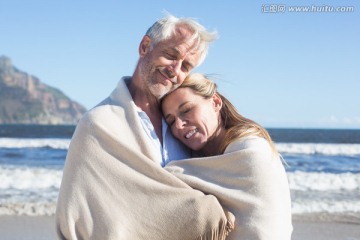 在沙滩上裹着毯子的夫妇