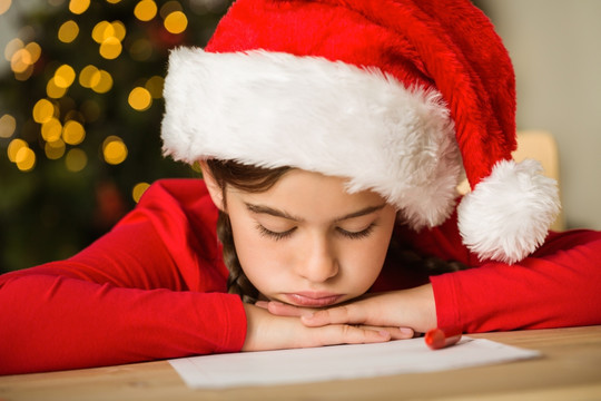 女孩趴在桌上准备给圣诞老人写信
