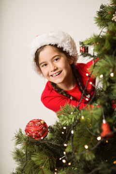 躲在圣诞树后面的小女孩