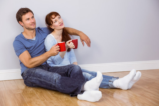 坐在地板上喝咖啡的一对夫妇