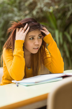 烦躁的女大学生在户外做作业