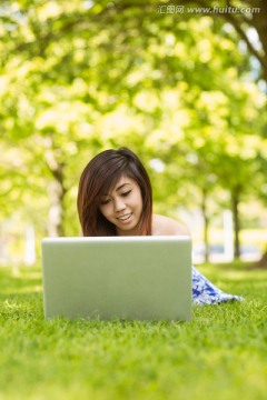 微笑的女人在公園里用筆記本電腦