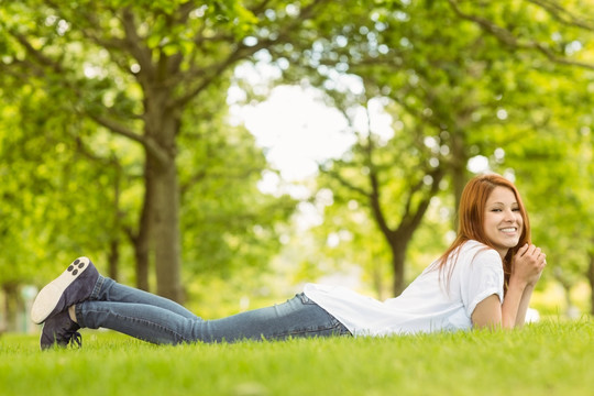 微笑的的女人趴在公园草地上