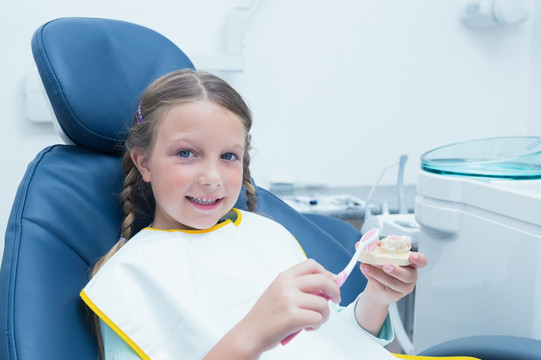小女孩在牙医椅上学习如何刷牙
