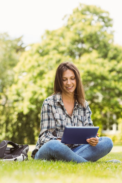 女人坐在公园里使用平板电脑