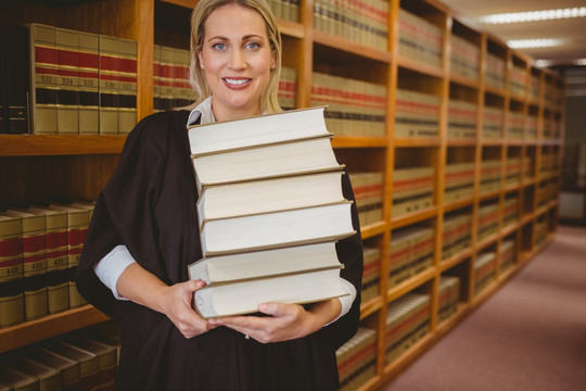 捧着一堆书的女律师在图书馆里