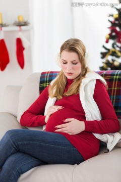 坐在沙发上摸着肚子的孕妇