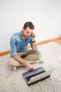 坐在地毯上使用笔记本电脑的男人