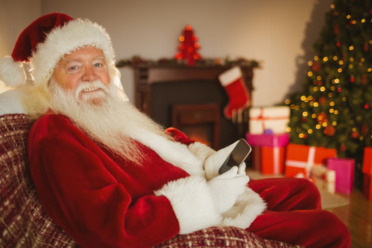 微笑的圣诞老人在使用智能手机