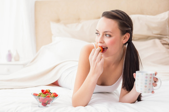 在床上吃草莓的女人