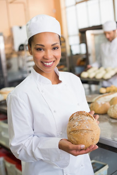 微笑的女面包师拿着一个面包