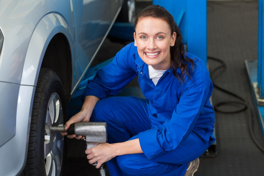 在汽车厂修理汽车轮胎的女修理工