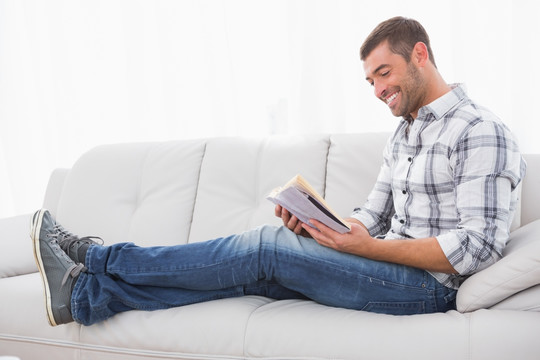 坐在家里的沙发上看书的男人