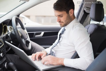 在车上使用笔记本电脑的男人