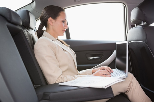 坐在车里使用笔记本电脑的女人