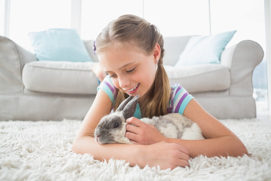 可爱的女孩在客厅里抱着兔子