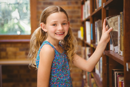 可爱的小女孩在图书馆里挑选书