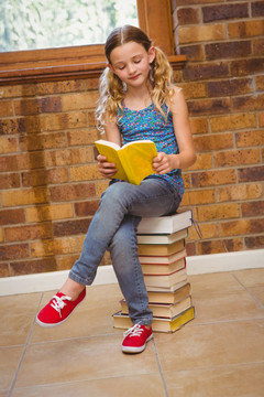 坐在一堆书上看书的小女孩