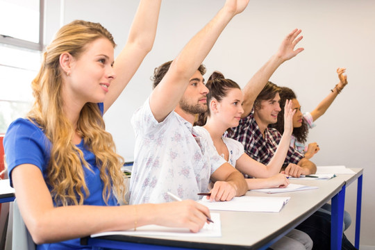 在大学教室里举手的学生们